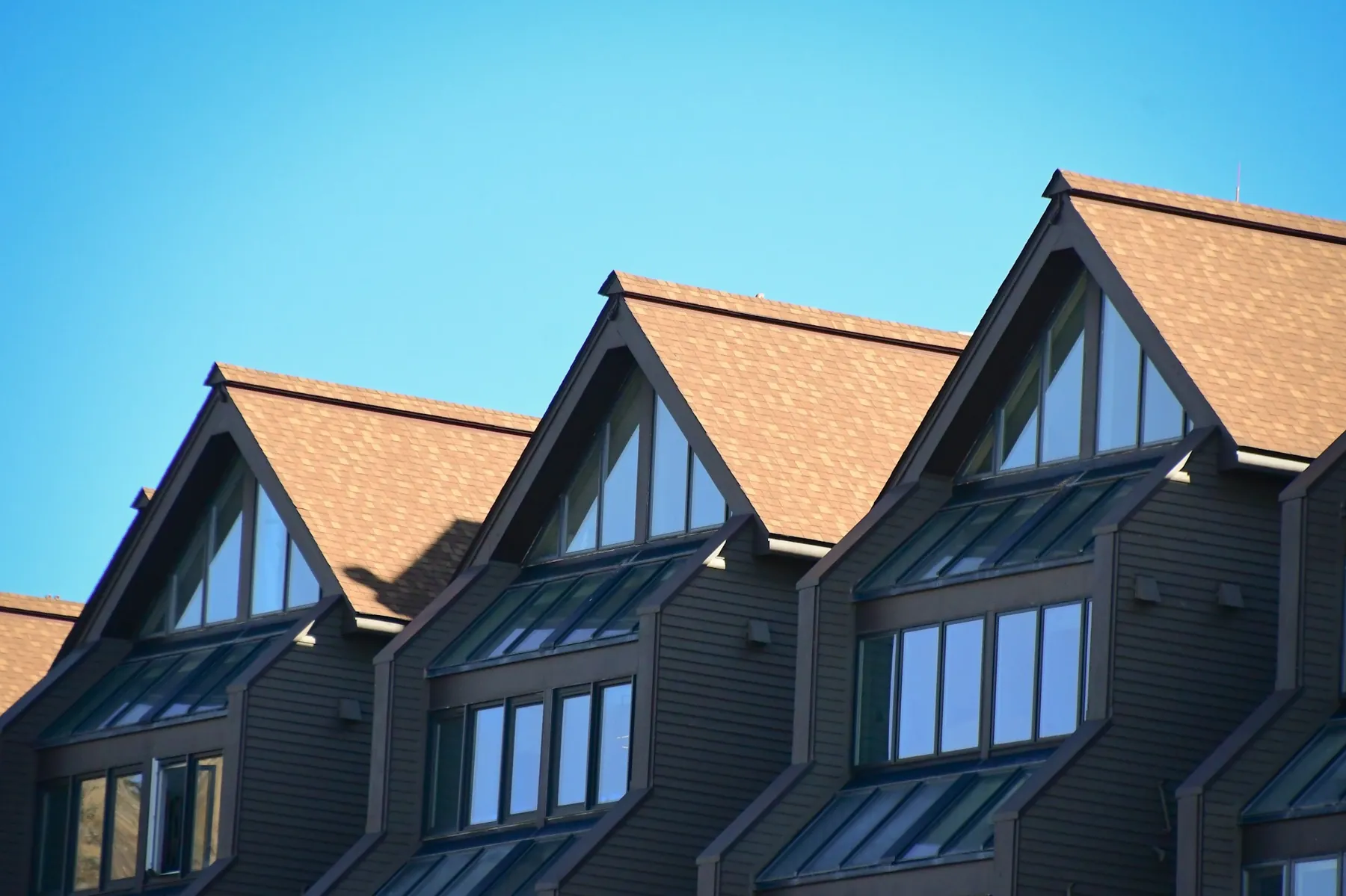 Row of roof gables against a clear blue sky